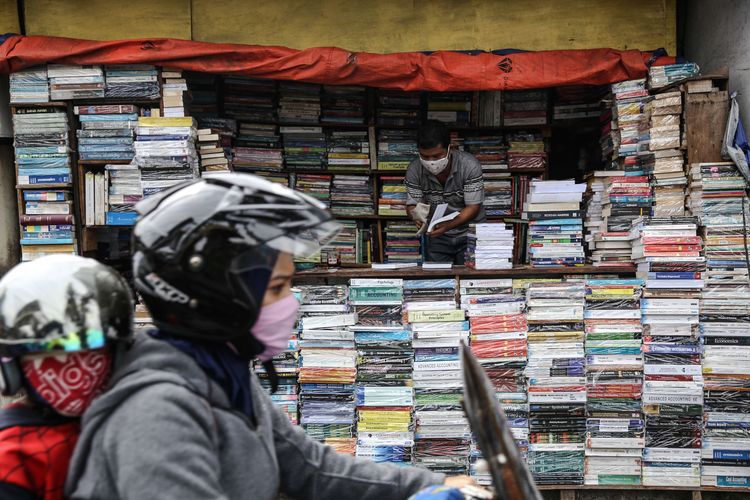 Warga menggunakan masker saat merapikan buku-buku di Jl. Letjen S. Parman, Jakarta Barat, Senin (4/5/2020). Provinsi DKI Jakarta memasuki pelaksanaan pembatasan sosial berskala besar (PSBB) yang diperpanjang ke tahap kedua. Tujuan PSBB ini adalah untuk menekan penyebaran virus corona (Covid-19).