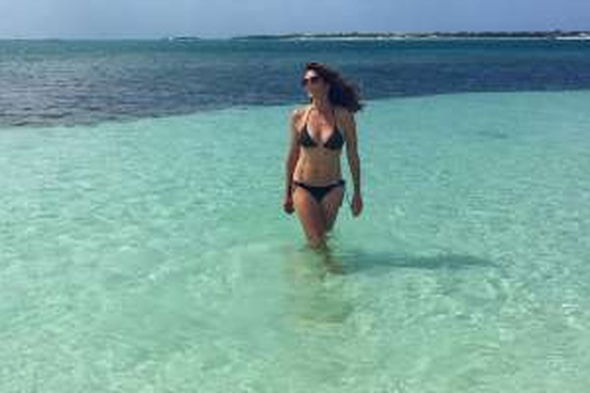 Foto Cindy Crawford tengah menikmati liburan di pantai mengenakan bikini mini yang seksi. 