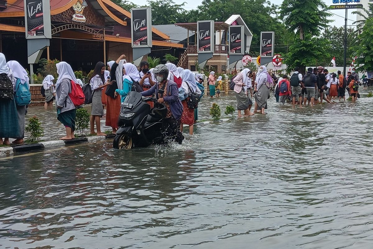 Seorang warga mendorong sepeda motornya melintasi banjir di Jalan Dr. Mansyur, Medan, Kelurahan Selayang I, Kecamatan Medan Selayang pada Kamis (18/8/2022).