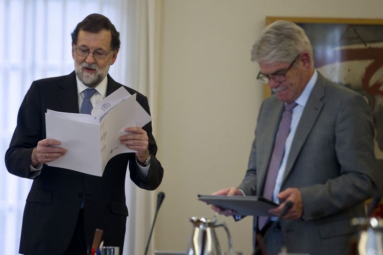 Perdana Menteri Spanyol Mariano Rajoy membaca dokumen di samping Menteri Luar Negeri Alfonso Maria Dastis (kanan) setelah rapat kabinet di istana La Moncloa, Madrid, Jumat (27/10/2017). Rajoy mengatakan bahwa pemerintahannya telah membubarkan parlemen Catalonia dan menggelar pemilihan daerah pada 21 Desember untuk mengatasi upaya pemisahan diri wilayah tersebut.