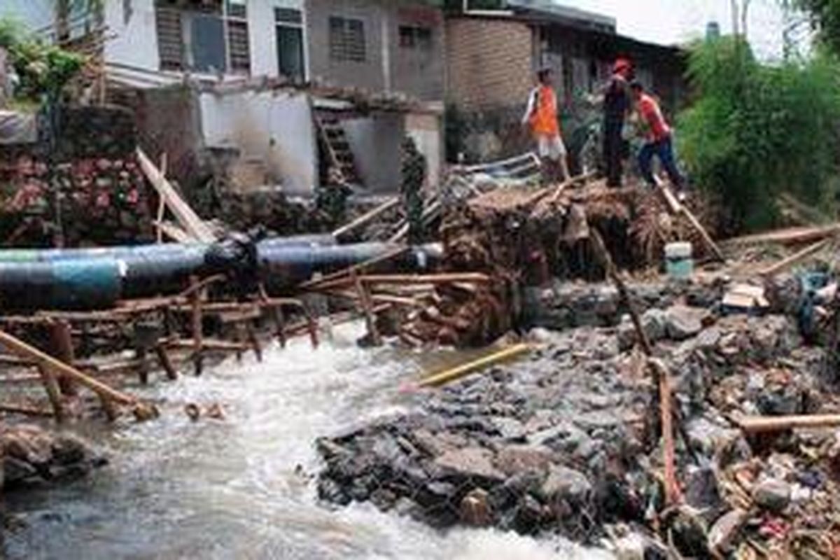 Sejumlah anggota TNI dari Koramil 06 Cimanggis, Jumat (16/11/2012), berusaha memasang pipa air darurat terbuat drum bekas untuk mengalirkan air di Kali Laya,  melintasi tanggul yang jebol. Pemkot Depok dinilai lamban memperbaiki tanggul yang jebol karena hingga empat hari sejak jebol Selasa lalu belum juga selesai.