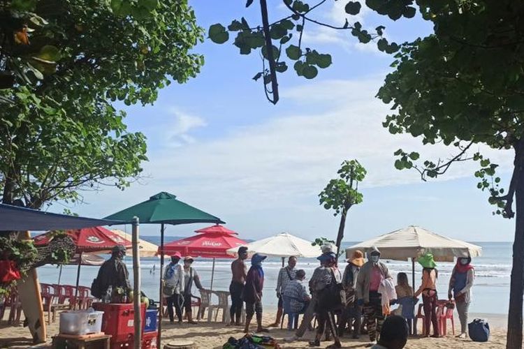 Tampak para pedagang sedang mengerumuni beberapa wisatawan asing yang sedang berjemur di Pantai Kuta, Badung, Bali. KOMPAS.com/Yohanes Valdi Seriang Ginta
