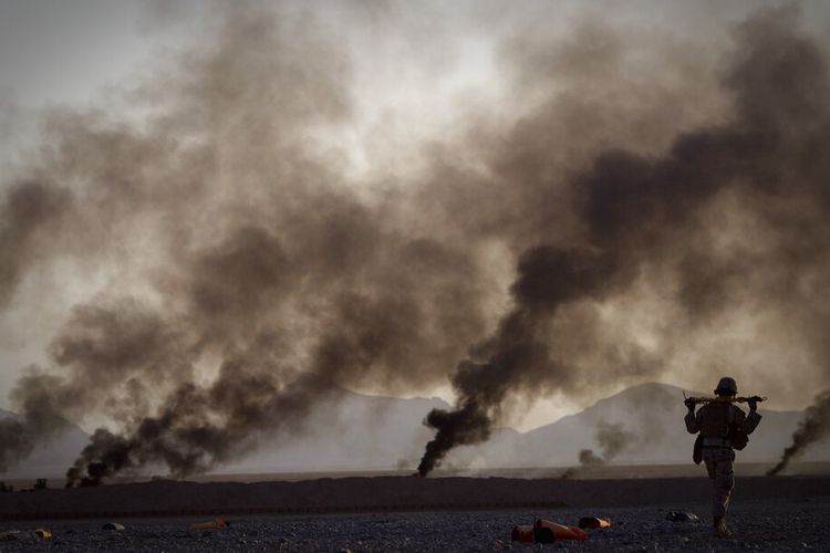 Dokumentasi seorang Marinir AS berjalan untuk mengambil persediaan makanan setelah mereka diturunkan dengan parasut kecil dari pesawat di luar Pangkalan Operasi Maju Edi di Provinsi Helmand Afghanistan selatan pada tanggal 9 Juni 2011. 