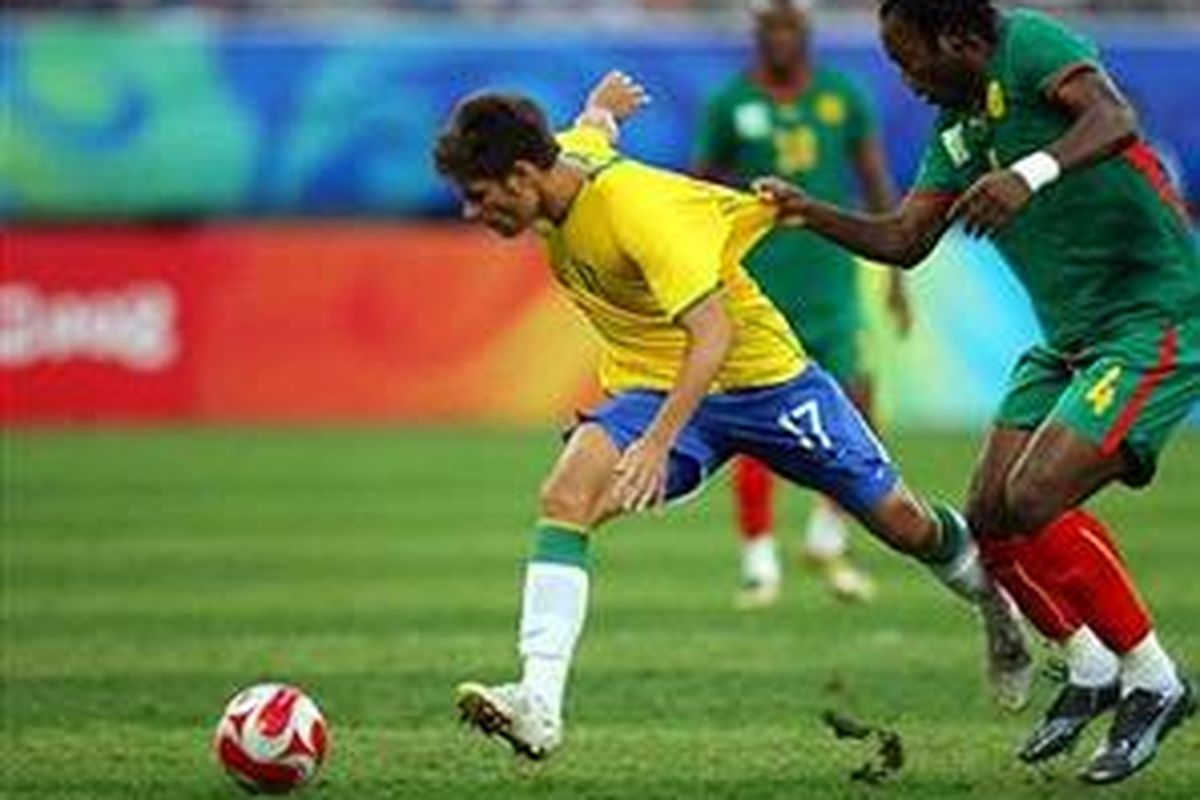 Pemain Brasil, Rafael Sobis (kiri), ditarik oleh pemain Kamerun, Andre Bikey. Brasil menang 2-0, dan gol pertama dicetak oleh Sobis.