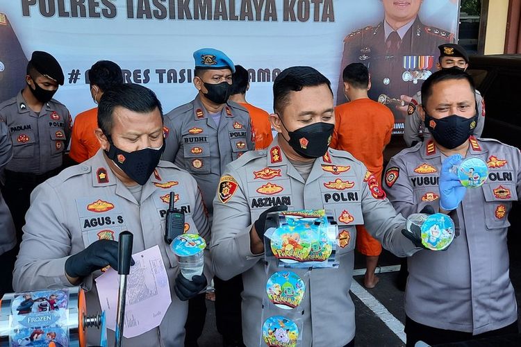 Kapolresta Tasikmalaya AKBP Aszhari Kurniawan, menunjukkan barang bukti dan tersangka pemilik pabrik produksi miras jenis ciu gelas kemasan plastik bergambar kartun, Senin (24/1/2022).