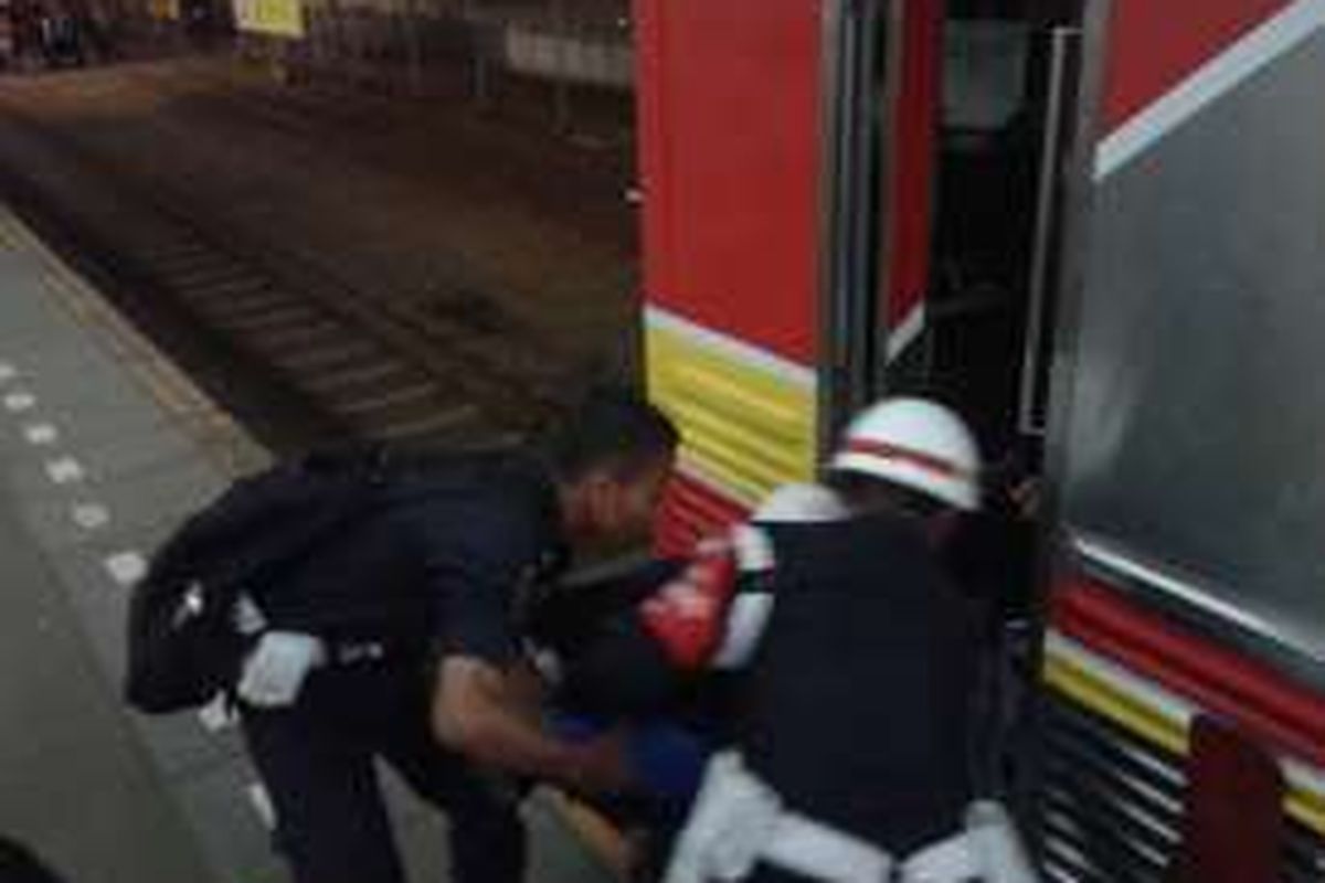 Rabu (6/4/2016) Petugas stasiun Tanah Abang mengevakuasi seorang wanita pingsan akibat tak kuat berdesak desakan di gerbong komuter line menuju Kampung Bandan