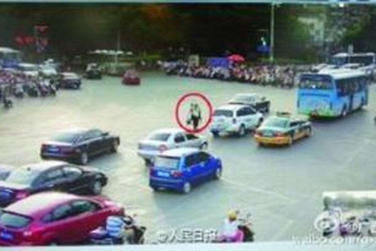 Dalam foto yang diambil dari kamera CCTV yang mengawasi sebuah perempatan di kota Luizhou, provinsi Guangxi, China ini terlihat seorang petugas polantas menggendong seorang pria yang terjebak di tengah arus lalu lintas karena tak bisa menyeberang.