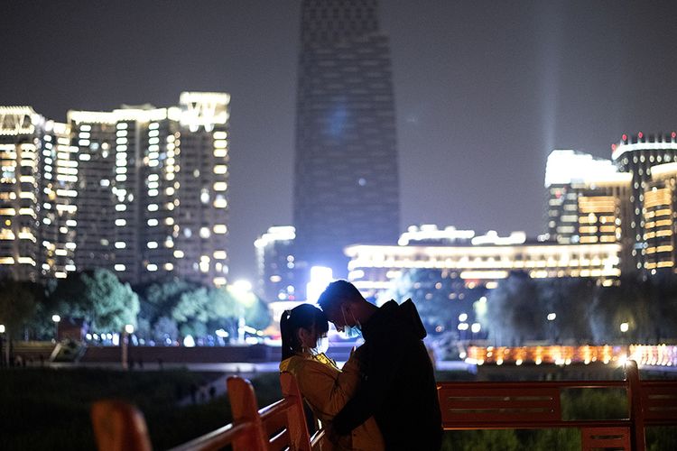 Pasangan kekasih mengenakan masker di taman tepi Sungai Yangtze di Wuhan, China, setelah kebijakan lockdown di wilayah itu baru-baru ini dicabut, Minggu (12/4/2020). Wabah virus corona tidak menghalangi momen bahagia sejumlah pasangan untuk tetap melangsungkan pernikahan, meski dilakukan dalam suasana sederhana dan sunyi.