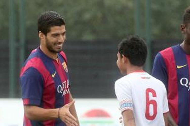 Striker Barcelona, Luis Suarez (kiri) saat bersalaman dengan kapten tim nasional Indonesia U-19, Evan Dimas, sebelum laga uji coba antara Barcelona B melawan Timnas U-19 di Ciutat Esportivo Joan Gamper, Rabu (24/9/2014).