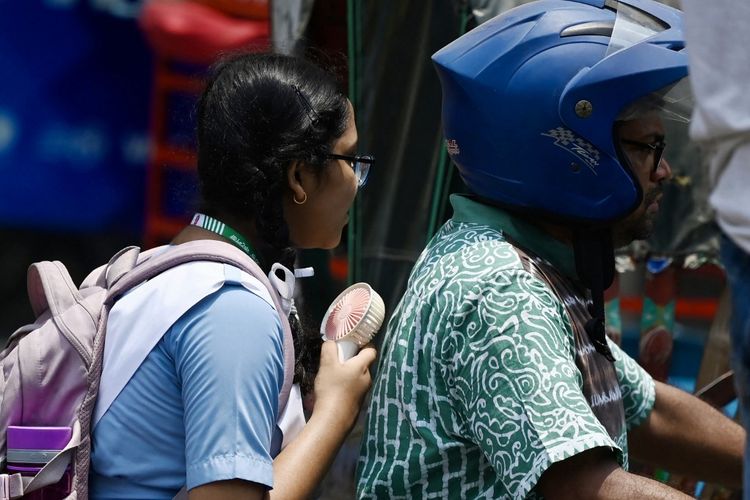 Seorang gadis mengendarai sepeda motor sambil menyalakan kipas portabel untuk mendinginkan diri saat gelombang panas di Bangladesh, tepatnya di Dhaka pada Selasa (6/6/2023).