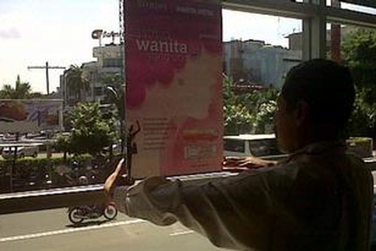 Kepala Badan Layanan Umum (BLU) Transjakarta, M. Akbar, memasang poster sosialisasi area khusus wanita di Halte Sarinah, Kamis (22/12/2011).