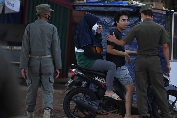 Anggota Satpol PP Kecamatan Cilandak menegur pengendara motor yang tidak memakai masker saat razia protokol kesehatan PPKM level 2 di Pondok Labu, Jakarta, Selasa (5/4/2022).