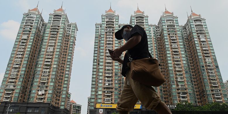 Seorang warga berjalan di depan properti milik Evergrande di Guangzhou, China. Foto diambil 17 September 2021.
