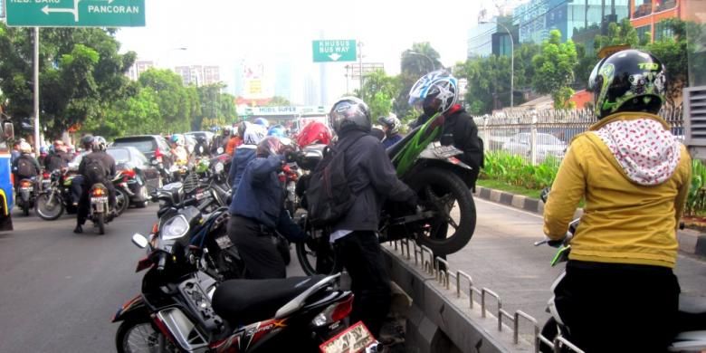 Pengendara motor di jalur transjakarta saling bahu membahu mengangkat motor yang terancam ditilang oleh polisi di kawasan Mampang, Jakarta Selatan, Kamis (21/11/2013).