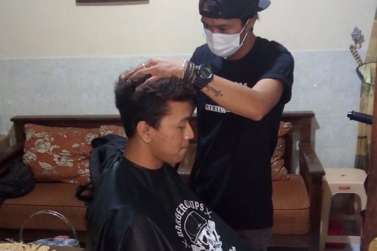 Ucup melayani jasa potong rambut panggilan di masa pandemi.