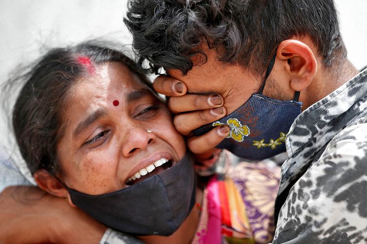 Seorang perempuan berduka dengan anak lelakinya setelah suaminya meninggal dunia akibat penyakit virus corona (Covid-19) di luar kamar mayat rumah sakit Covid-19 di Ahmedabad, India, Selasa (20/4/2021). India dihantam kengerian dengan lonjakan kasus Covid-19 mencetak rekor tertinggi dunia melampaui 17 juta kasus.