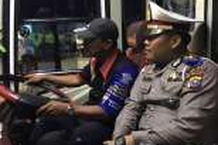 Seorang petugas polisi mengawal bus langsung di atas kendaraan yang melewati jalan lintas Sumatera ruas Minas - Kandis yang rawan kecelakaan. 
