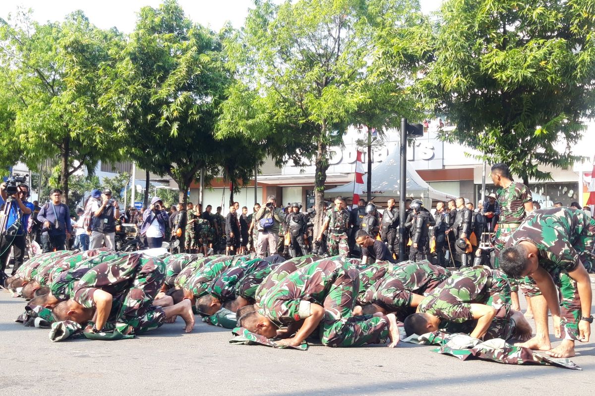 TNI AD shalat dengan beralaskan seragamnya di wilayah Bawaslu RI, Jakarta Pusat, Rabu (22/5/2019)