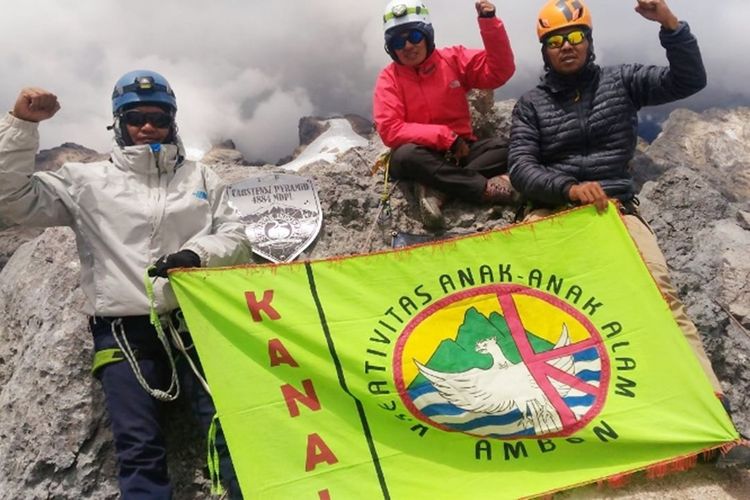 Tiga anggota pendaki asal Maluku Rosna Pesilett (tengah), Koko Handoko (kiri) dan Budi Herman (kanan) mengibarkan bendera organisasinya saat  berada di atas puncak Cartnesz, Papua, 14 September 2019. foto dok Rosna Pesilette