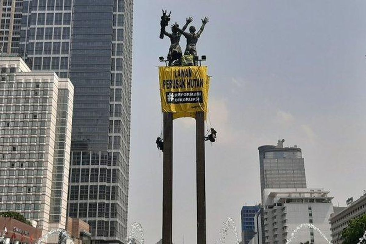 Empat orang membentangkan spanduk atau kain rentang di ujung patung Bundaran Hotel Indonesia, Jakarta Pusat, pada pukul 09.00 WIB, Rabu (23/10/2019).