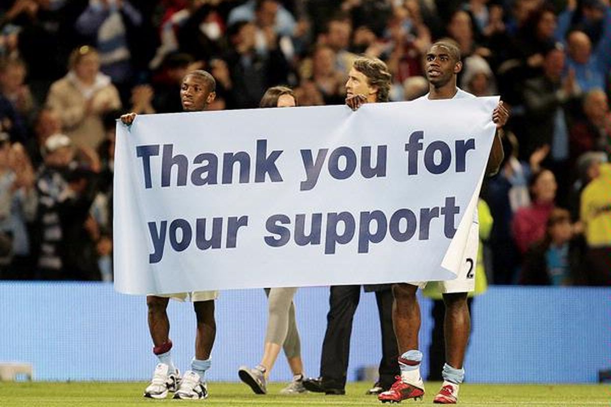 Pemain Manchester City, Micah Richards (kanan) dan Shaun Wright-Phillips (kiri), berkeliling lapangan dengan banner yang mengucapkan terima kasih usai laga melawan  Stoke City di Stadion The City of Manchester, Inggris, Selasa (17/5).