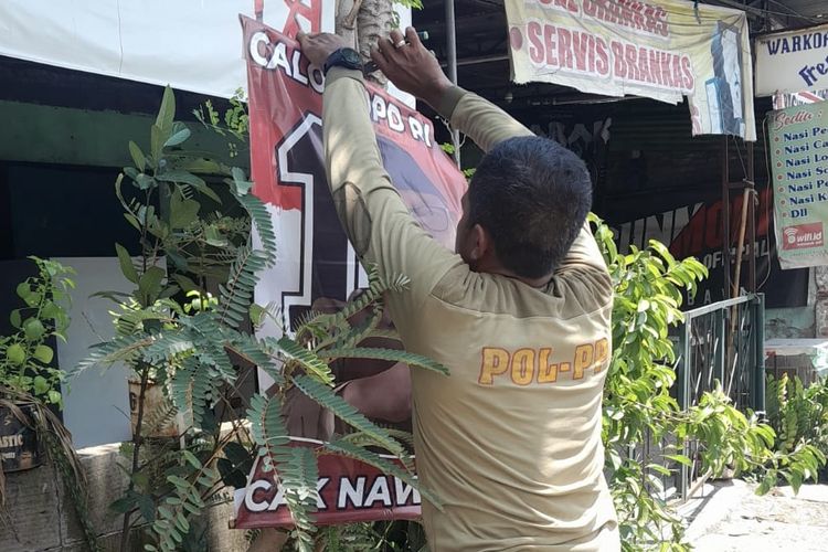 Anggota Satpol PP Surabaya saat bersihkan APK, Senin (12/2/2024).