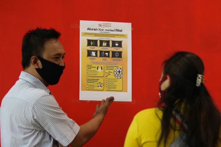 Pegawai swalayan Carrefour menunjukkan poster kepada pengunjung usai ditempel di BG Junction, Surabaya, Jawa Timur, Rabu (27/5/2020). Penempelan poster yang berbunyi Aturan New Normal Ritel itu agar pengunjung memahami protokol pencegahan penularan COVID-19 saat mengunjungi pusat perbelanjaan. ANTARA FOTO/Didik Suhartono/foc.
