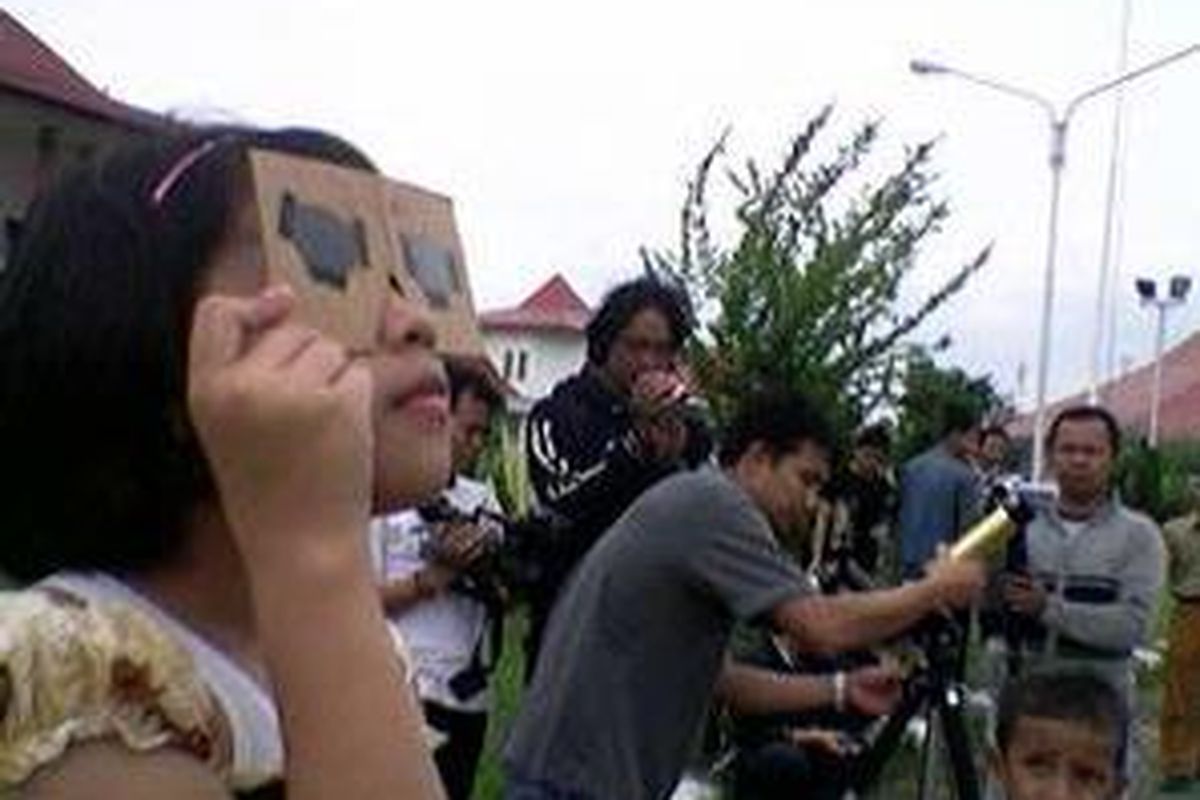 Anak-anak di Palembang, Sumatera Selatan, melihat gerhana matahari dengan menggunakan kacamata buatan sendiri yang terbuat dari film disket, Senin (26/1).