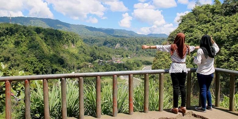 Dua wisatawan asal Pekanbaru, Riau, menikmati pemandangan dari puncak Janjang Seribu, Kota Bukittinggi, Sumatera Barat, Sabtu (25/4/2015). Potensi wisata, baik alam maupun budaya, yang sangat besar menjadi sektor penting dalam menunjang pembangunan Bukittinggi. Sektor tersebut menyumbang sekitar 62 persen bagi pendapatan asli daerah kota yang terkenal dengan ikon Jam Gadang ini.
