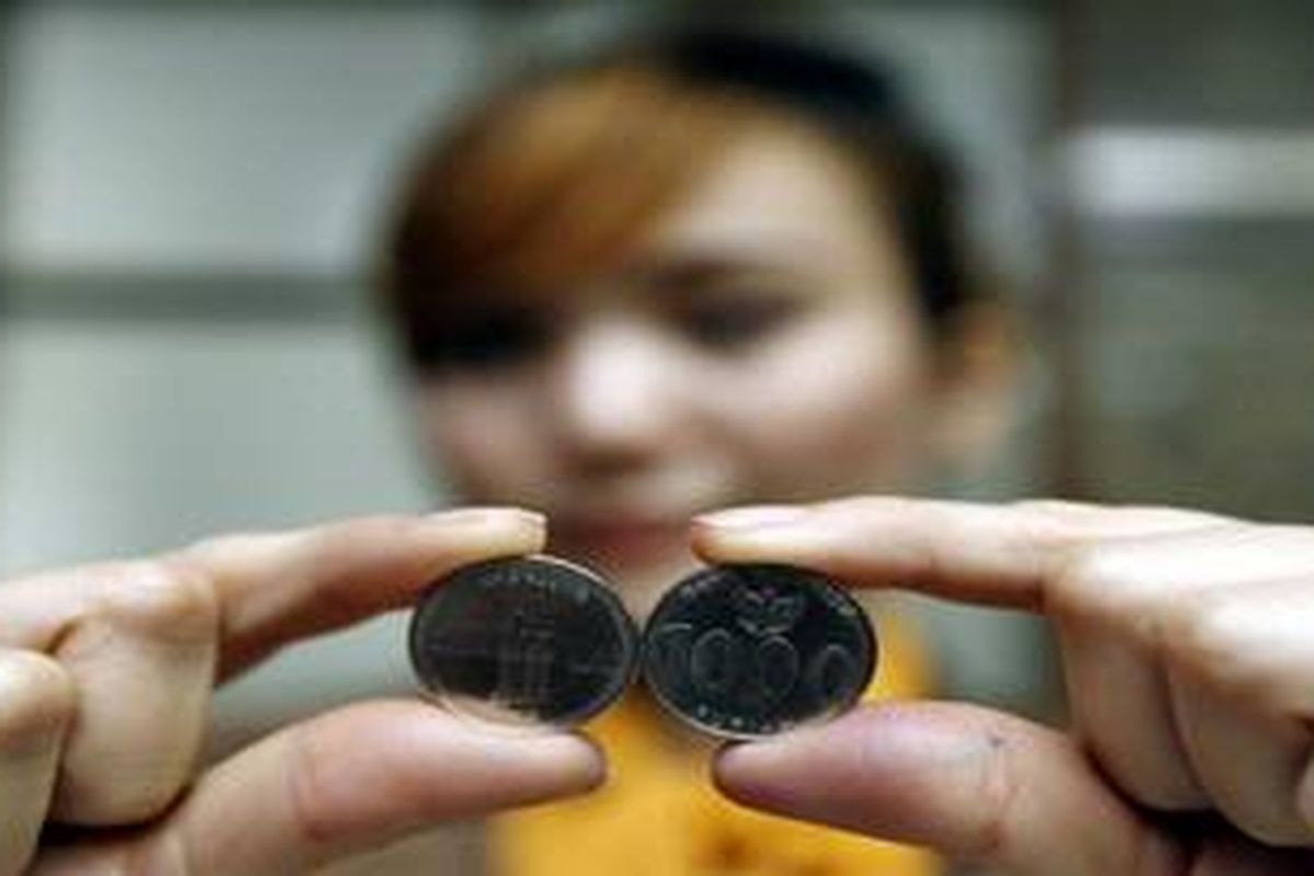Teller menunjukkan dua wajah mata uang logam pecahan Rp 1.000 saat peluncuran di Gedung Bank Indonesia Bandung, Jawa Barat, Selasa (20/7/2010). Bagian depan uang logam ini bergambar Garuda Pancasila dan bagian belakang bergambar angklung dengan latar belakang Gedung Sate.