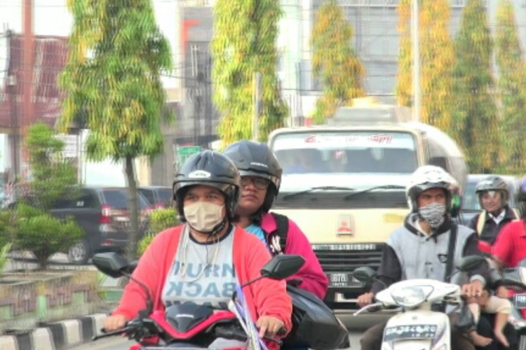 Sejumlah pengendara sepeda motor di Jalan Sultan Hasanuddin, Kota Dumai mengenakan masker akibat dampak kabut asap karhutla, Senin (18/2/2019).