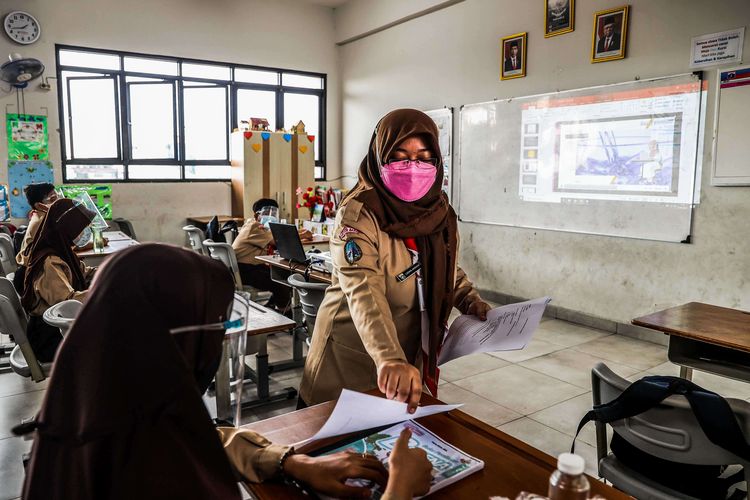 Guru memberikan materi pelajaran kepada murid saat uji coba pembelajaran tatap muka pada hari pertama di SDN 03 Palmerah, Jakarta Barat, Rabu (7/4/2021). Pembelajaran tatap muka (PTM) di wilayah PPKM level 3 Jawa-Bali masih mengacu Surat Keputusan Bersama (SKB) 4 Menteri tentang Panduan Penyelenggaraan Pembelajaran pada Masa Pandemi Covid-19 dengan menggelar PTM terbatas dengan jumlah peserta didik 50 persen dari kapasitas ruang kelas dan pembelajaran jarak jauh (PJJ).