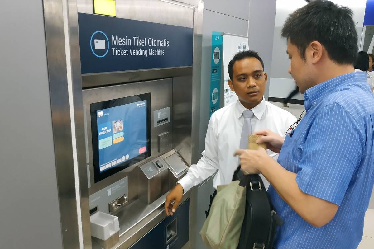 Seorang petugas di Stasiun Bundaran HI sedang mendampingi penumpang yang hendak membeli tiket melalui  mesin tiket otomatis.