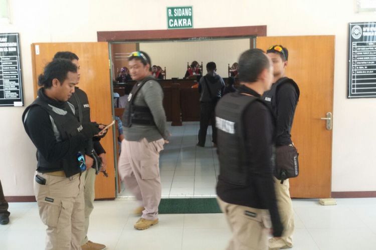 Aparat polisi bersenjata lengkap terlihat berjaga-jaga di depan pintu ruang sidang kasus bentrok anggota dua perguruan pencak silat di Pengadilan Kabupaten Madiun, Selasa ( 4/7/2017).