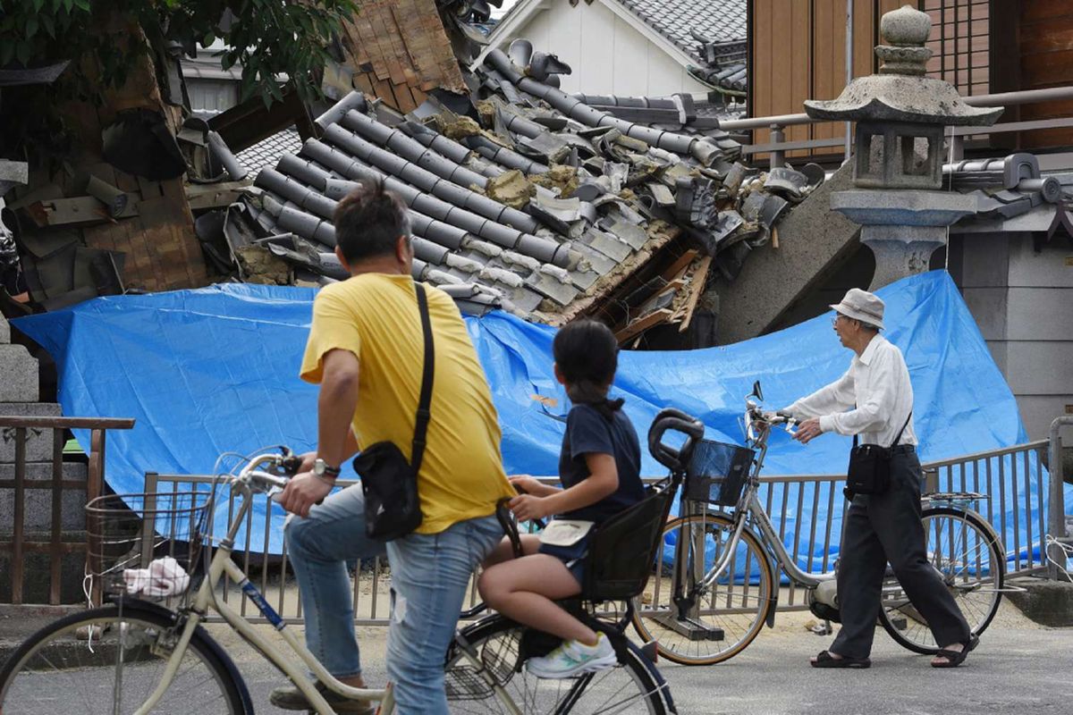 Warga berhenti untuk melihat kerusakan pada sebuah rumah yang hancur akibat gempa bumi di Ibaraki, Utara Osaka, Senin (18/6/2016). 2 orang tewas dan ratusan lainnya terluka akibat gempa berkekuatan 5,3 magnitudo dengan pusat kedalaman 15,4 km.