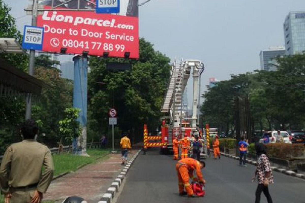 Petugas pemadam kebakaran berupaya menurunkan seorang pria yang memanjat papan reklame di Jalan HR Rasuna Said, Kuningan, Jakarta, Jumat (26/5/2017). Polisi menutup sementara jalur lambat di Jalan HR Rasuna Said untuk memudahkan petugas pemadam kebakaran.