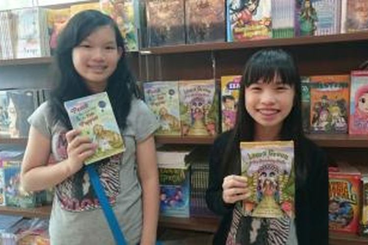 Si Kembar Jessica (kiri) dan Jennifer (kanan) memegang buku fiksi karya masing-masing.  Jaringan Toko Buku Gramedia di seluruh Jabodetabek menjual buku karya mereka sejak Mei 2015.