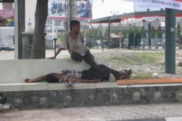 Dua gepeng ini sedang beristirahat di sebuah halte yang berada dekat dengan simpang empat Kota Bireuen. (DESI)