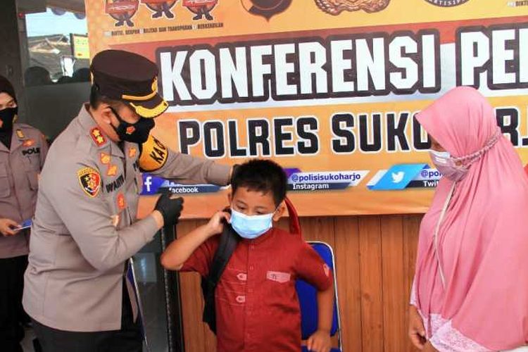 Kepala Polres Sukoharjo AKBP Wahyu Nugroho Setiawan memberikan perlengkapan sekolah kepada anak asuh, Ashar Al Gifari Putra Setiawan (8), yang kehilangan kedua orang tuanya karena Covid-19 di Mapolres Sukoharjo, Selasa (27/7/2021).