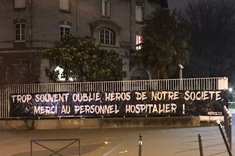 Spanduk yang dibentangkan para Ultras PSG di depan RS Pitie-Salpetriere, rumah sakit terbesar di Perancis, untuk mendukung perang melawan pandemi virus corona. Spanduk itu berbunyi Terlalu sering dilupakan, pahlawan masyarakat kita, terima kasih kepada semua staff di rumah sakit.