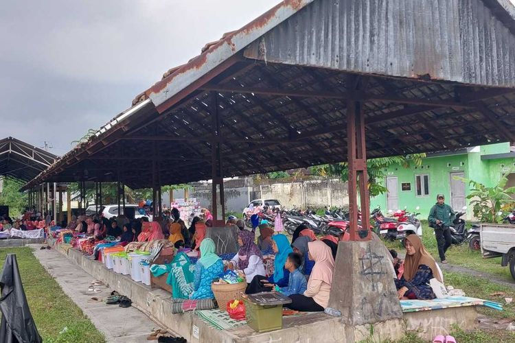 Para warga perempuan di Padukuhan Saren, Kalurahan Wedomartani, Kapanewon Ngemplak, Kabupaten Sleman saat mengikuti acara tradisi Nyadran Pasar. Mereka duduk di los Pasar Wonosari dan tepat didepanya terdapat berbagai makanan yang dibawa dari rumah untuk disantap oleh warga bersama-sama.