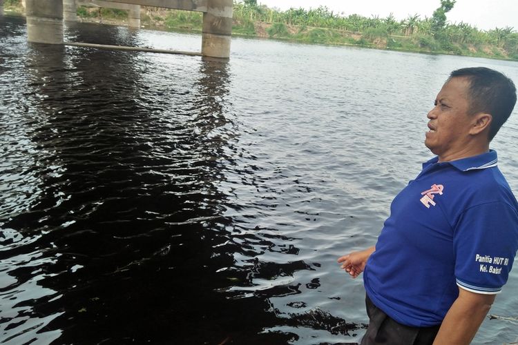 Trisno saat menunjukkan air di aliran Bengawan Solo, yang berubah coklat kehitaman.