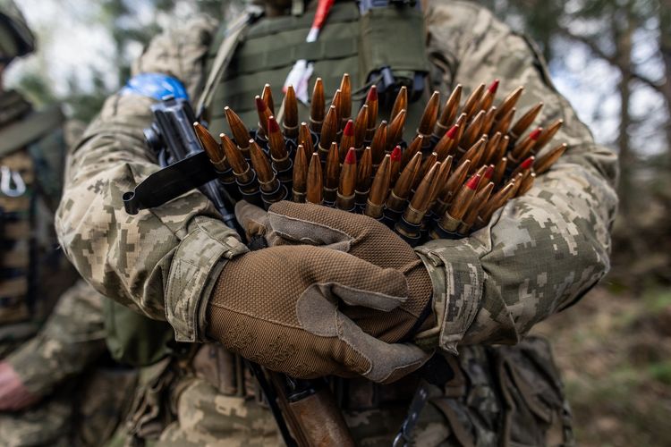 Tentara Ukraina membawa amunisi senapan mesin saat latihan militer bersama pasukan Perancis di lokasi yang dirahasiakan di Polandia pada 4 April 2024. Latihan militer ini berlangsung di tengah perang Rusia-Ukraina yang telah berkecamuk lebih dari dua tahun.