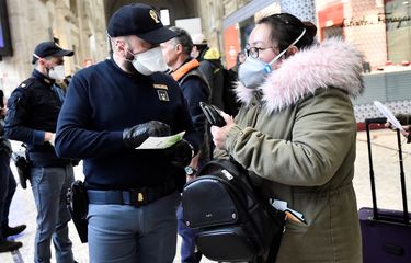 Seorang polisi yang mengenakan masker melakukan pemeriksaan terhadap calon penumpang di stasiun kereia utama di Milan, Italia, pada 9 Maret 2020. Pemerintah Italia menerapkan karantina buntut virus corona yang merebak.