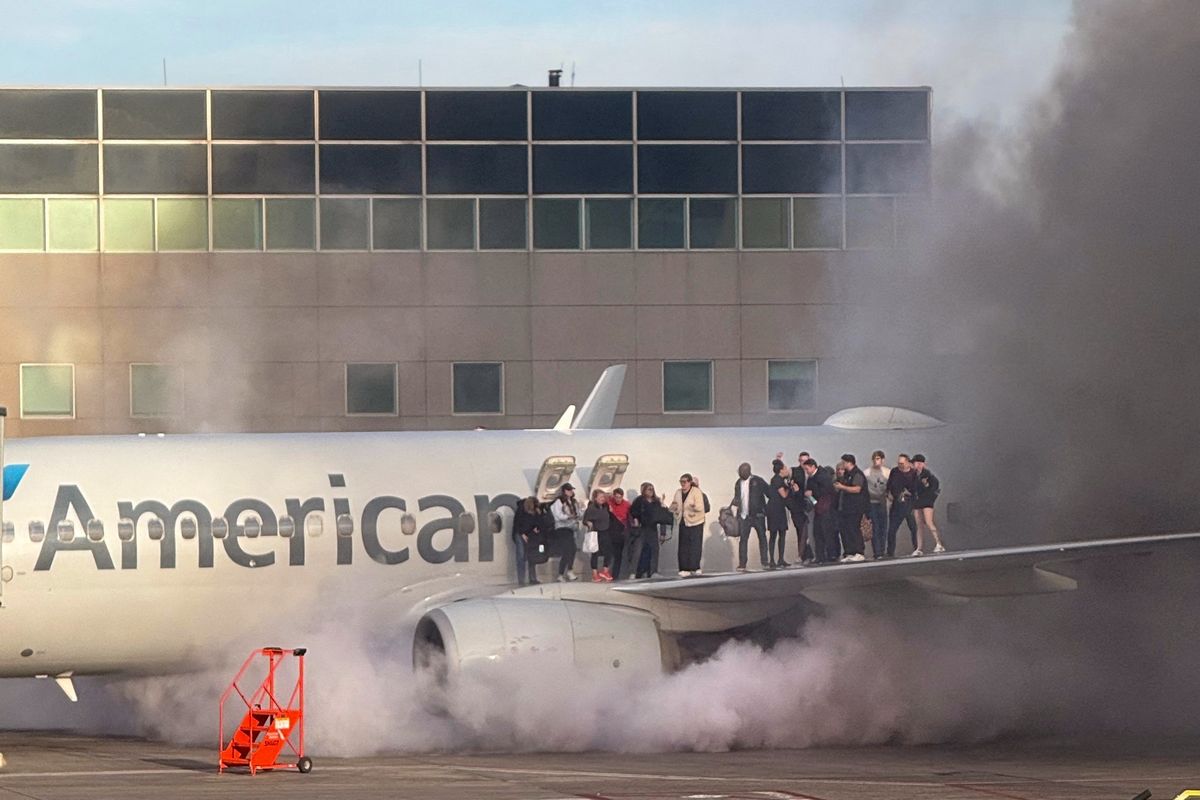 Penumpang American Airlines berdiri di sayap setelah pesawat itu terbakar di Bandara Internasional Denver, Negara Bagian Colorado, Amerika Serikat, 13 Maret 2025.