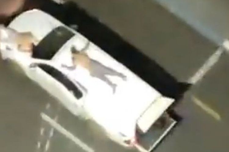 Perampok bank di Brasil yang menggunakan sandera sebagai tameng, memaksa sanderanya berbaring di atap dan kap mobil, sambil mengancam akan menembak wajah sanderanya jika tidak berpegangan.