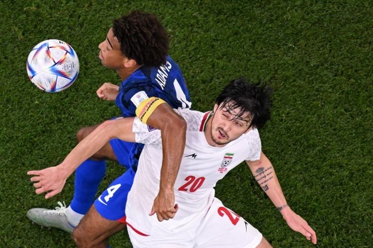 Duel antara Sardar Azmoun (20) dengan Tyler Adams (4) dalam laga Grup B Piala Dunia 2022 Iran vs Amerika Serikat di Stadion Al-Thumama, Doha, 29 November 2022. (Photo by Kirill KUDRYAVTSEV / AFP)