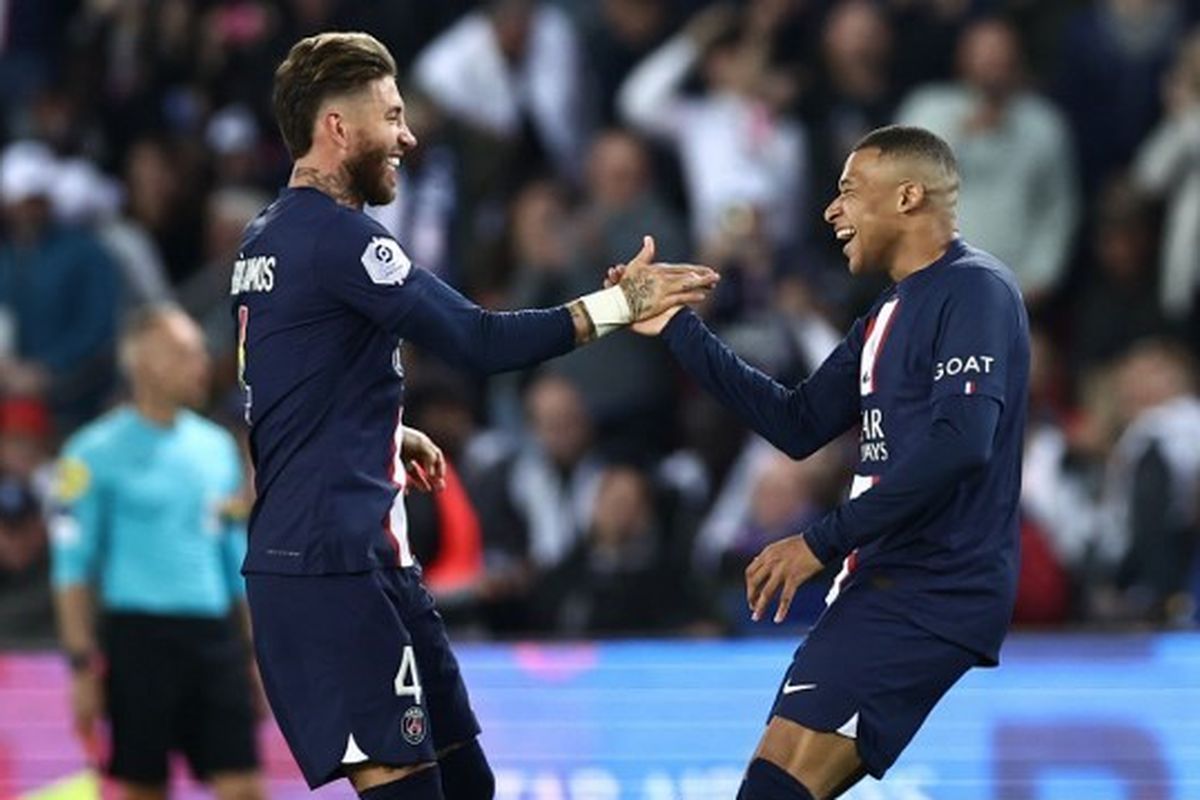 Penyerang Paris Saint-Germain (PSG), Kylian Mbappe (kanan), merayakan gol bersama Sergio Ramos dalam pertandingan melawan Ajaccio pada pekan ke-35 Liga Perancis 2022-2023. Laga PSG vs Ajaccio yang digelar di Stadion Parc des Princes, Paris, pada Sabtu (13/5/2023) malam waktu setempat tersebut berakhir dengan skor 5-0 untuk kemenangan PSG. (Foto oleh Anne-Christine POUJOULAT / AFP)