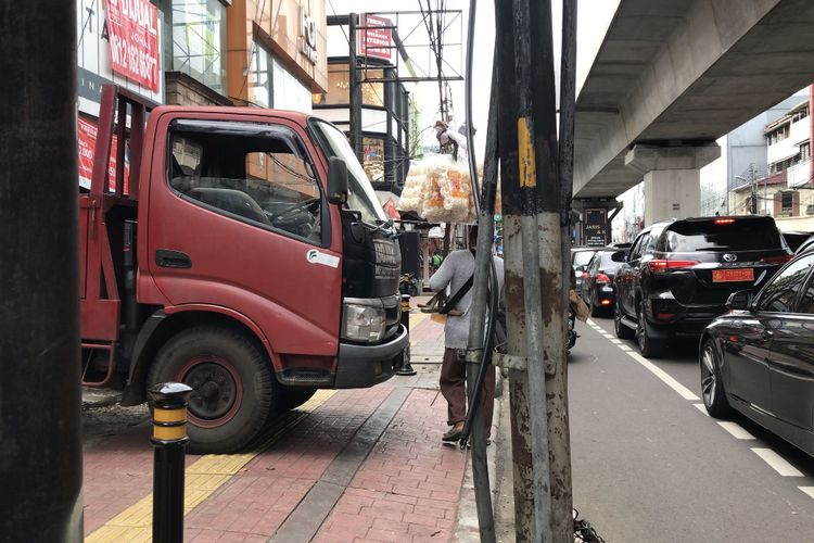 Ridwan (40), tunanetra penjual krupuk berjalan menjauhi jalur Yellow Line setelah menabrak truk yang parkir hingga melewati jalur khusus penyandang disabilitas di Jalan Panglima Polim, Pulo, Jakarta Selatan pada Jumat (26/2/2021) sore.