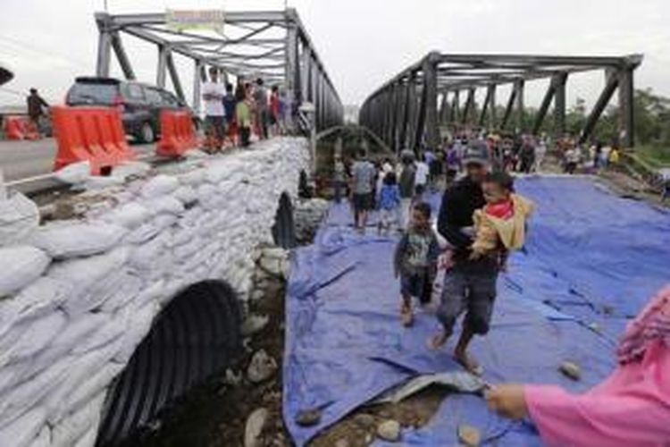 Warga menyaksikan dibukanya kembali Jembatan Comal Pantura, Pemalang, Jawa Tengah, di jalur barat ke timur, Kamis (24/7/2014). Lalu lintas untuk jalur timur ke barat masih diarahkan ke jalan alternatif, karena sisi jembatan selatan masih belum selesai diperbaiki.